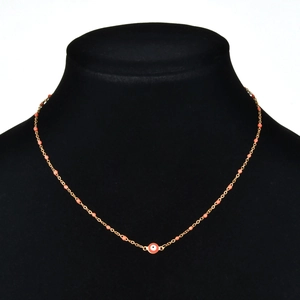 Detail of gold evil eye necklace with orange beads displayed on a black neck model
