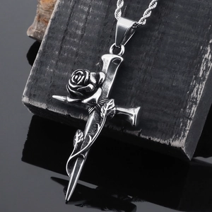 Close-up of vintage stainless steel cross and rose pendant on black wood base