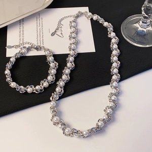Detailed shot of stainless steel necklace and bracelet set with white pearls and lobster clasp