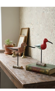 Artistic hand-painted wooden long-billed bird figurines on a vintage cabinet