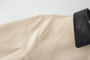 Close-up of contrast beige woven fabric and black leather collar stitch details