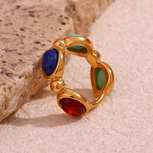 Detail of gold-plated stainless steel rings with vibrant oval natural stones on rock