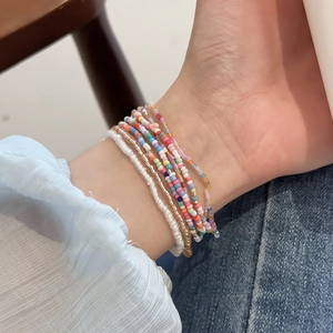 Detail of colorful bohemian seed bead layered bracelet set worn on model wrist