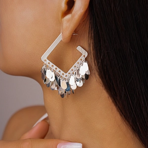 Detail of silver square drop earrings with dangling sequins shown on model's ear