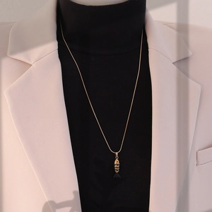 Gros plan d'un collier pendentif carpe koï dorée rétro sur un col roulé noir