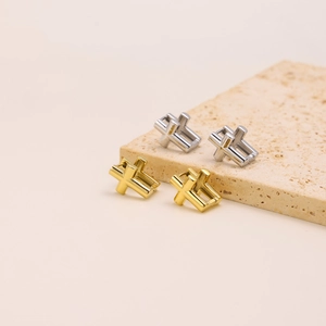Detailed shot of hollow cross stud earrings in gold and silver finish on stone