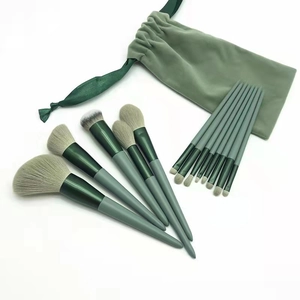Detailed set of 13 forest green makeup brushes with a soft velvet storage bag