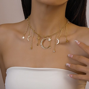 Détail du collier doré multicouche avec étoiles, lune pavée de cristaux et perle