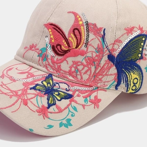 Detail of sequined butterfly and floral embroidery on a beige baseball cap fabric