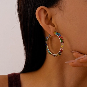 Close-up of a large silver hoop earring with rainbow colored glass beads on female model