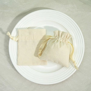 Detailed view of beige cotton linen drawstring pouches on a white ceramic plate