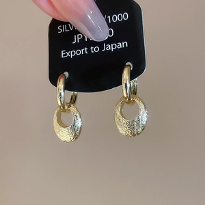 Detail of vintage gold-plated earrings with textured hammered finish on card