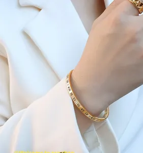 Close-up of gold roman numeral bangle with diamonds and matching hollow ring on model
