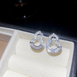 Macro shot of silver hollow gourd stud earrings with zircons on jewelry box lining