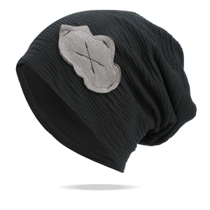 Detail view of black slouchy beanie featuring a cloud patch and ribbed knit texture