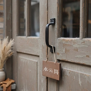 Close-up of vintage cast iron door handle with matte texture on aged wood surface