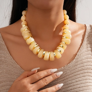 Detail of yellow acrylic beaded necklace with marbled texture and gold metal spacers