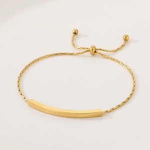 Detailed macro view of the LOVER DREAM engraving on the adjustable gold slider bracelet