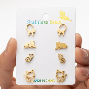 Detailed view of four pairs of golden stainless steel cat earrings on a display card