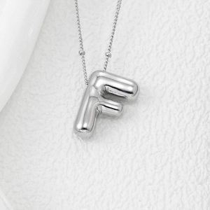 Macro shot of 3D silver puffy letter F balloon pendant necklace on a minimalist chain