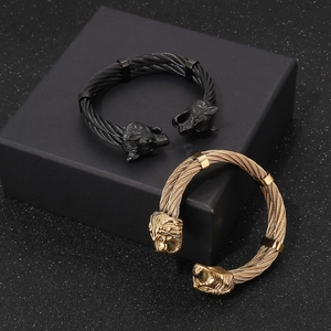 Detail of punk style braided wire bracelets featuring lion and wolf head motifs in gold and black