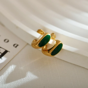 Elegant gold C-shaped earrings with green oval enamel inlay on a white textured backdrop