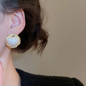 Primo piano di orecchini a cuore in perla placcati oro 16K indossati da una modella