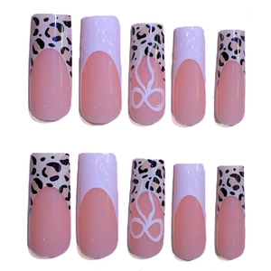 Detailed flat lay of 10 leopard print French tip press-on nails with white 3D bow designs