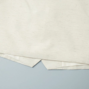 Detailed close-up of white cotton linen fabric texture and stitching on the vest hem