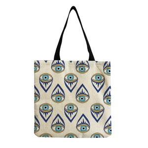 Detail view of canvas tote bag with evil eye patterns and black fabric straps