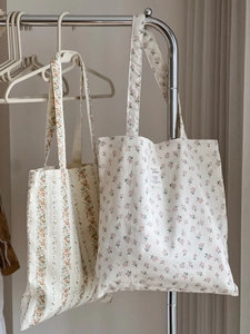Detail of two floral cotton tote bags in pink and orange hanging on a metal rack