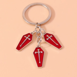 Detail of three red coffin charms with silver crosses on a metal keychain accessory