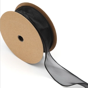Close-up of black sheer chiffon ribbon with pleated edges on a craft paper spool