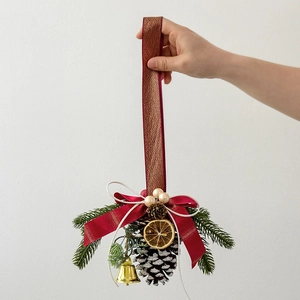 Handmade Christmas pine cone ornament with red bow, golden bell and lemon slice