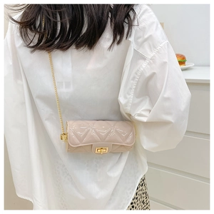 Quilted nude cylinder bag with gold chain strap shown on model in a stylish casual look