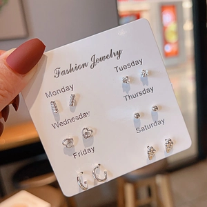 Silver earring set of 6 pairs on a Monday-Saturday card held by a hand