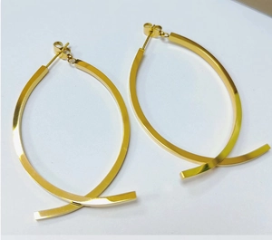 Close-up of minimalist cross curved 18K gold earrings set against a white background