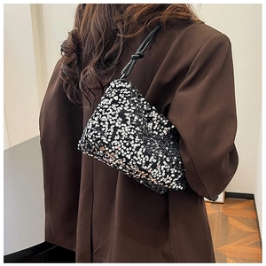 Detail of silver sequin shoulder bag with black braided rope handle on brown blazer