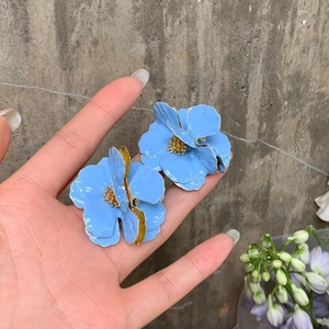 Macro detail of sky blue flower earrings with golden edges and beaded metal centers
