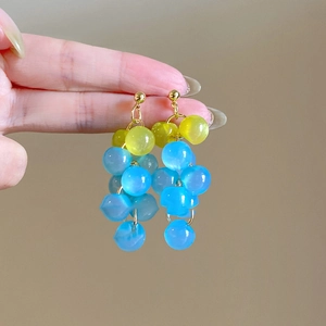 Détail des boucles d'oreilles à perles jaunes et bleues montrant la longueur