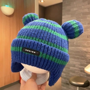 Detail of blue and green striped knit baby hat with ear flaps and cute ear decorations