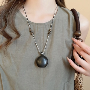 Close-up of vintage ethnic necklace with black wood gourd pendant and beads