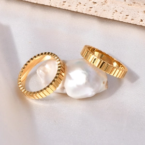 Golden pleated gear rings set with radial texture on a baroque pearl display