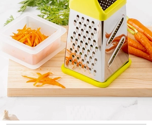 Detail of a four-sided stainless steel grater shredding carrots on a wooden board