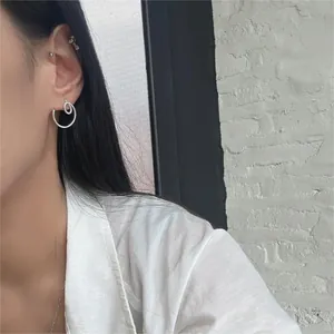 Close-up of minimalist S925 sterling silver spiral double-loop earring on female model