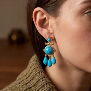 Vintage gold earrings with turquoise stone round pendant and teardrop charms on a model