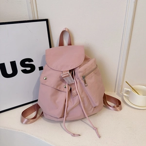 Detail of pink nylon backpack featuring drawstring closure and silver buckle hardware