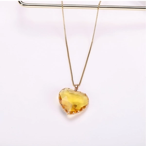 Macro detail of yellow heart crystal pendant with faceted glass on a gold metal chain