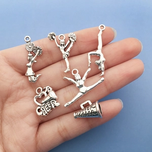 Detailed view of six silver alloy cheerleading charms held in hand with blue background