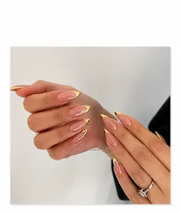 Detail of nude almond press-on nails with golden metallic French tips on hands